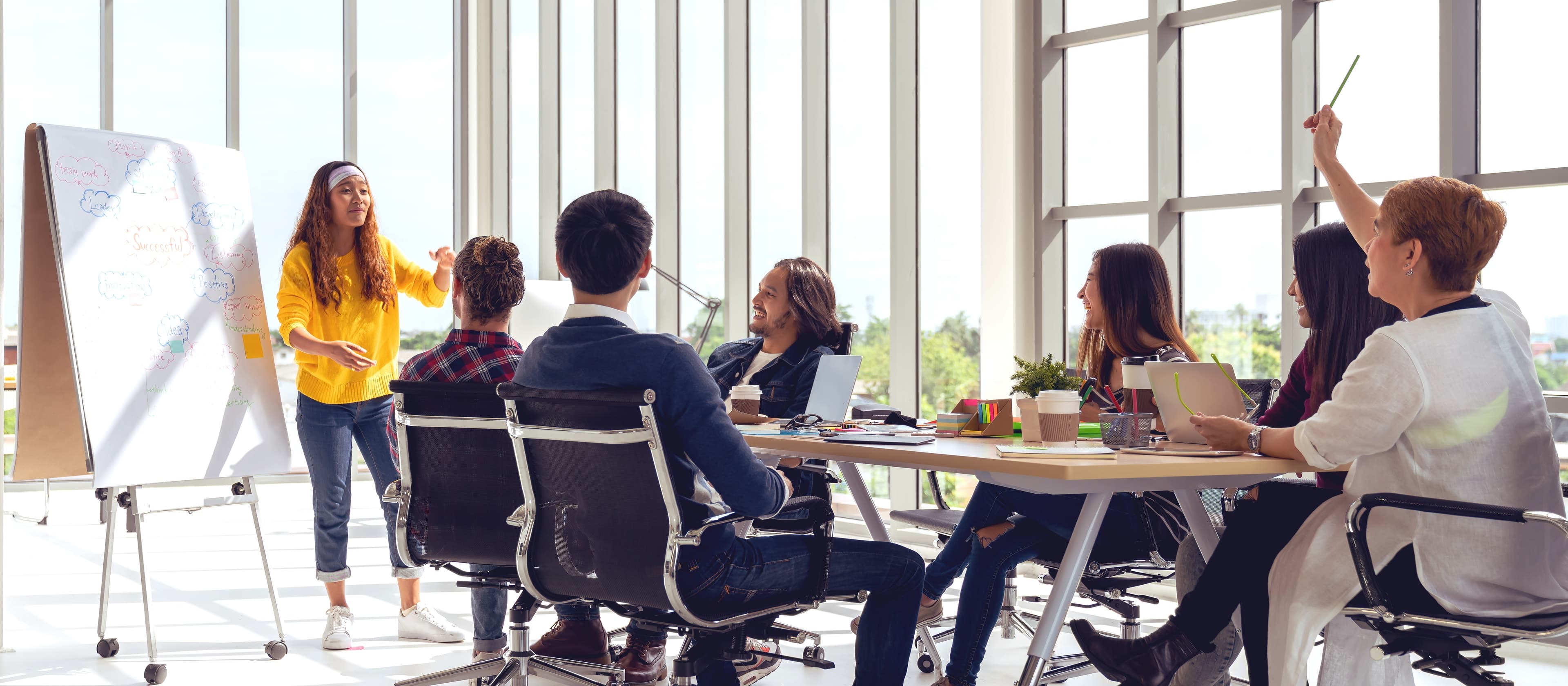 A facilitator presenting at a whiteboard to a seated team.
